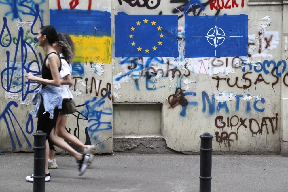 Two women walk past graffiti of the Ukrainian, EU and NATO flags in Tbilisi’s old town, 22 May 2023. Photo: EPA-EFE/ZURAB KURTSIKIDZE